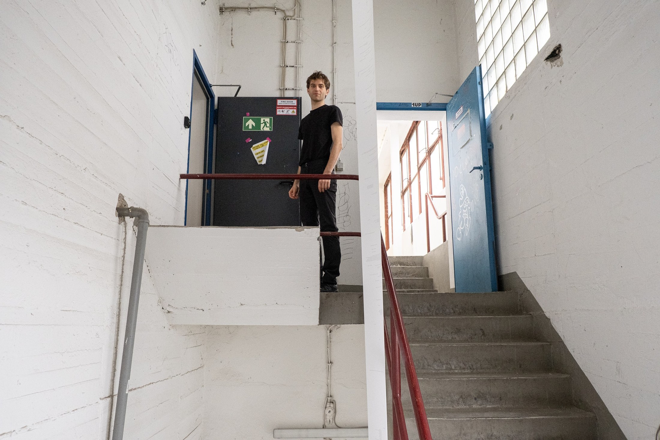 Hendrik Arns standing on a landing in a white concrete stairwell.